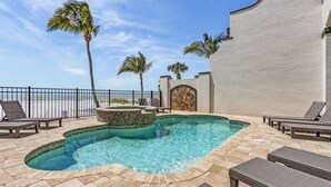 A pool area with lounge chairs, palm trees, and a view of the ocean. - 3134 Estero Blvd 5 Bedroom Home by RedAwning (Fort Myers Beach)