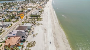 An aerial view of a coastal area with a beach, residential buildings, and a road. - 3132 Estero Blvd 5 Bedroom Home by RedAwning (Fort Myers Beach)