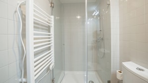 A modern bathroom with a glass-enclosed shower, a white radiator, and a toilet. - Home with a Pool by Vacationy (Porto)