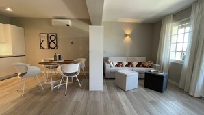 En moderne stue med sofa, skammel og spiseområde med stole og et bord.