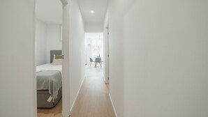 Ein schmales Entree mit einem Bett links und einem Tisch mit Stühlen in der Ferne.