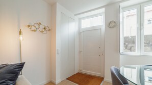 Ein modernes Wohnzimmer mit einem Glastisch, einer Couch und einer Tür zu einem weiteren Raum.