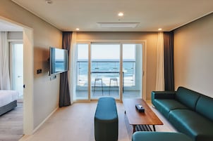 A hotel room with a balcony, a bed, a sofa, a table, and a TV.
