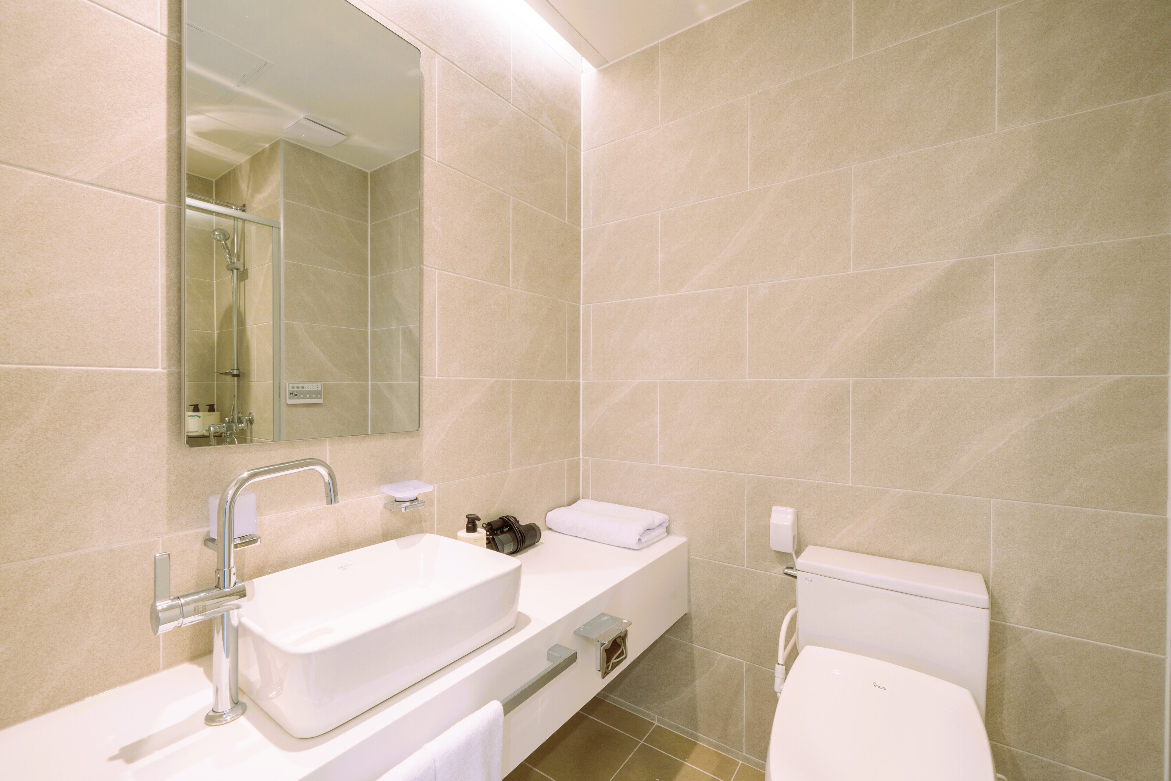 A bathroom with a white sink, mirror, and toilet.