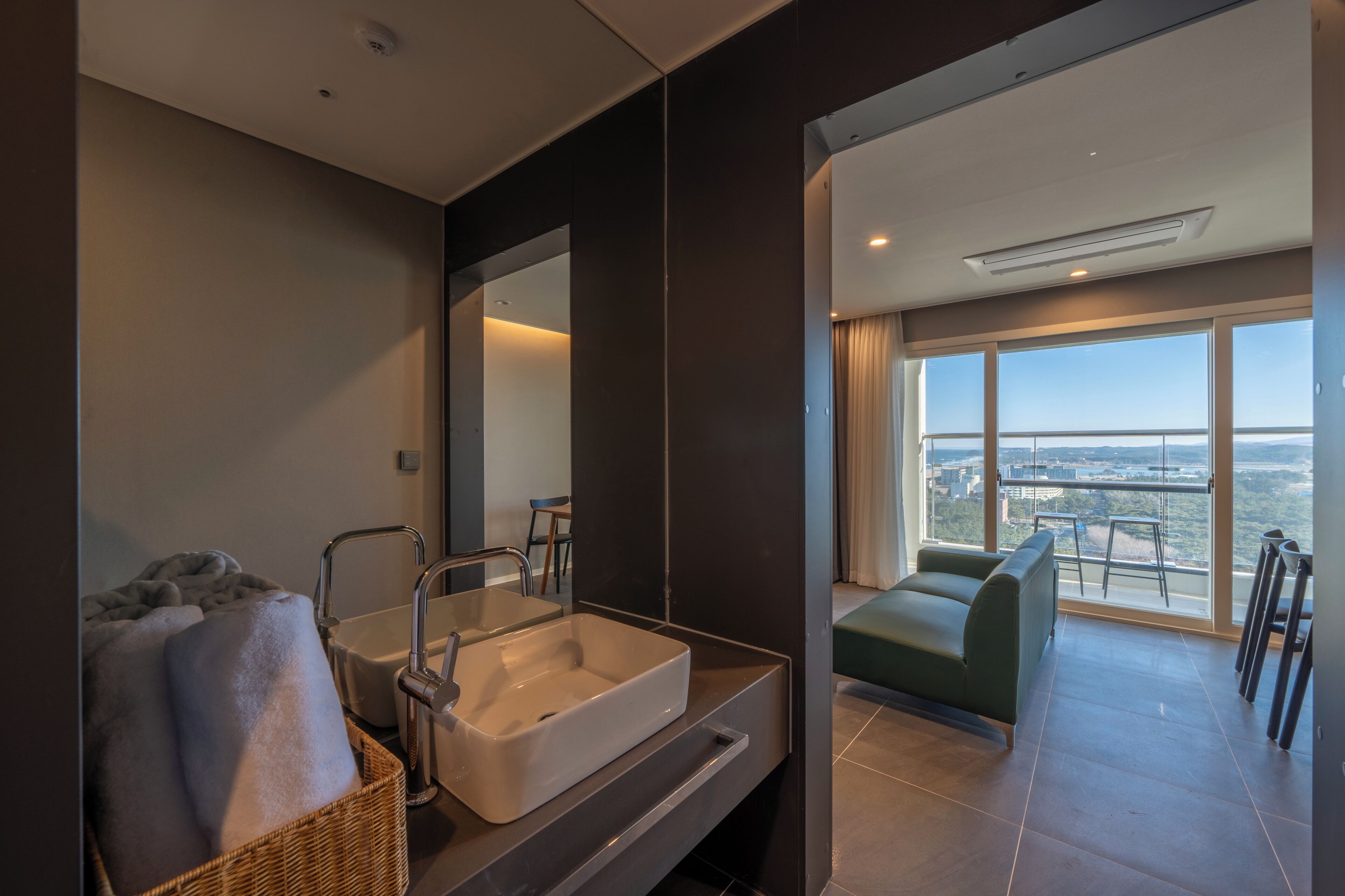 A modern bathroom with a large bathtub, a mirror, and a view of a cityscape through a large window.