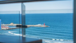 Vista sulla costa con un faro, mare calmo e un edificio con tetto rosso.