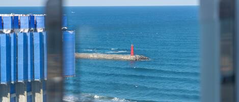 A coastal view with a lighthouse, ocean, and a pier with blue structures.