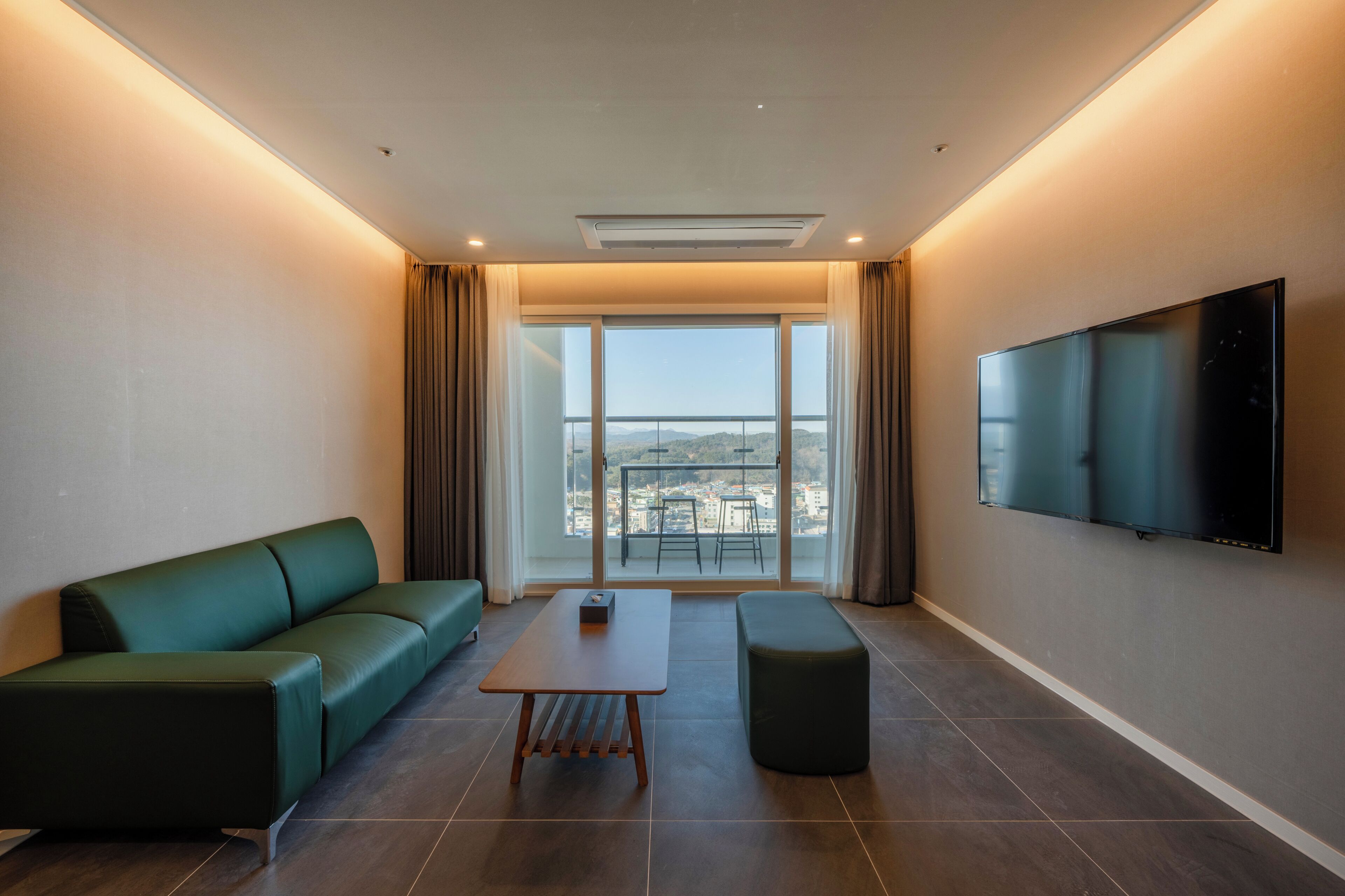A modern living room with a sofa, a coffee table, and a TV mounted on the wall.