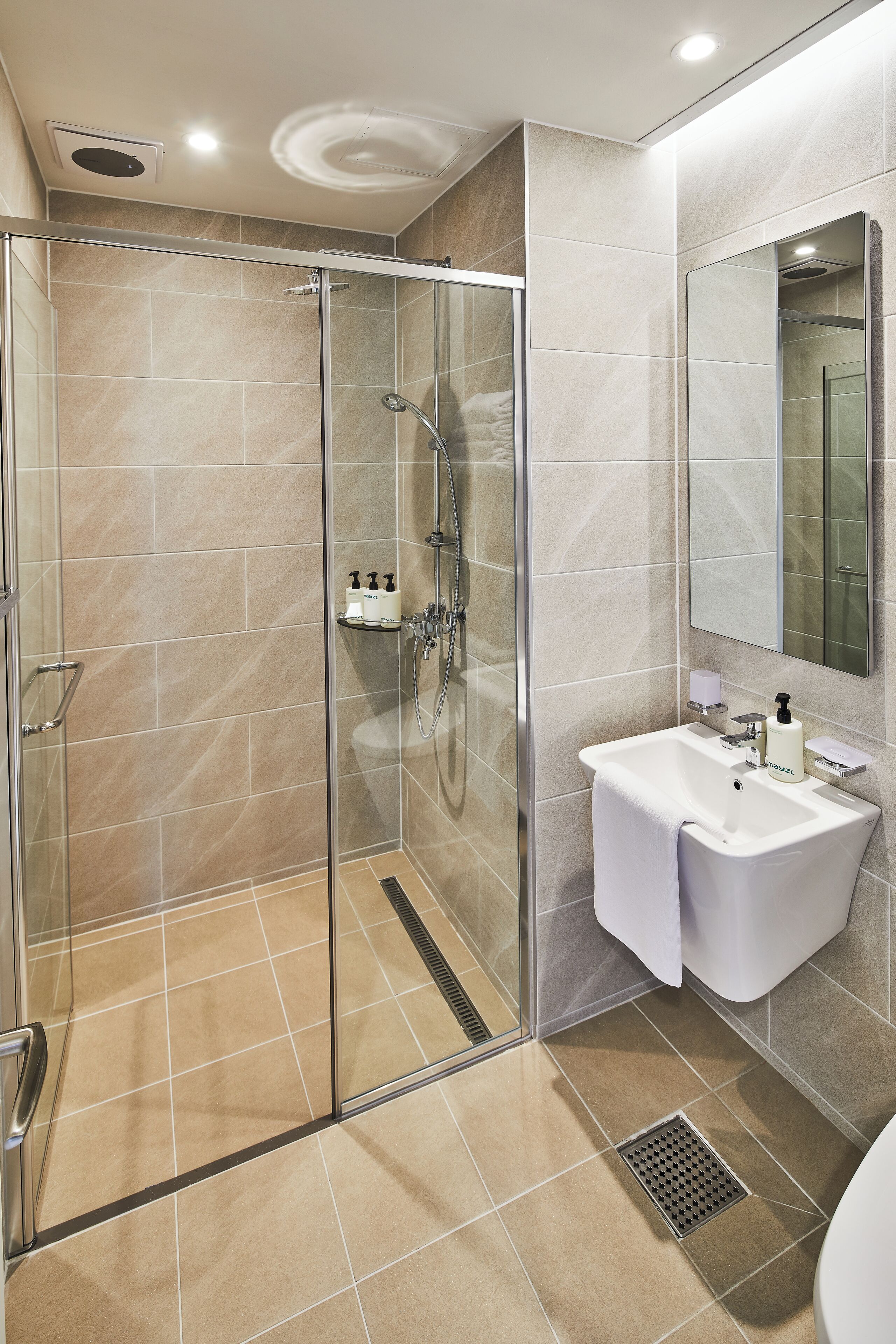 A modern bathroom with a glass shower enclosure, a white sink, and a large mirror.