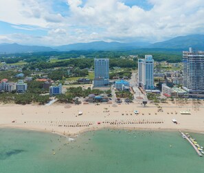 Un paisaje urbano costero con edificios altos, una playa de arena y un cielo despejado.
