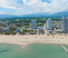 A coastal cityscape with high-rise buildings, a sandy beach, and a clear sky.