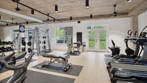 Une salle de sport spacieuse équipée de divers appareils d’exercice, notamment des tapis de course, des appareils de musculation et des poids libres.