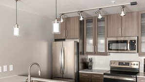 A modern kitchen with stainless steel appliances, a central island with a sink, and pendant lighting. - Austin Gorgeous 1BD 1BA Downtown Apartment (Austin)