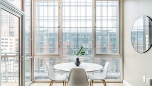 A modern dining area with a round table, white chairs, and a potted plant. - Austin Gorgeous 1BD 1BA Downtown Apartment (Austin)