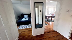 A hallway leading to a bedroom with a bed, a mirror, and a dining area with a table and chairs. - Ferienwohnung Apartment No. 9 in Husum für bis zu 2 Personen (Husum)