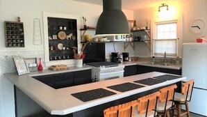Une cuisine dotée d’un îlot central, de tabourets de bar, d’un luminaire suspendu et d’une horloge murale.