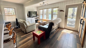 Un salon spacieux comprenant un canapé, un fauteuil, une table à manger et un téléviseur.