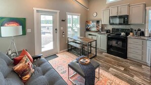 A compact living space with a kitchenette, a dining area, and a sofa with cushions. - Bear Hug Cabin (Ruidoso Downs)