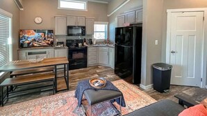 A modern kitchen with a dining area, a large TV, and a cozy seating area. - Bear Hug Cabin (Ruidoso Downs)