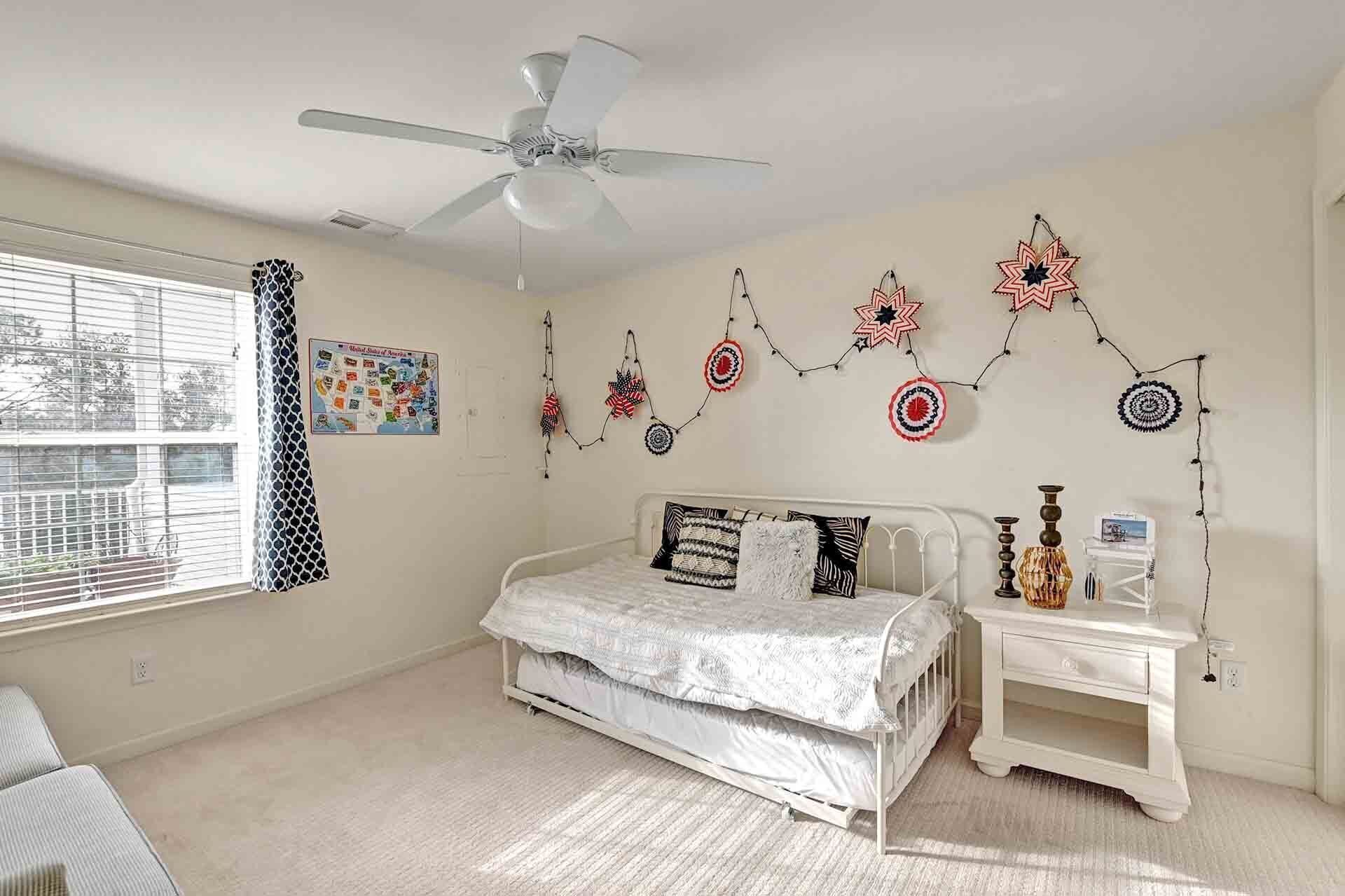 A bedroom with a bed, a nightstand, a ceiling fan, and wall decorations.