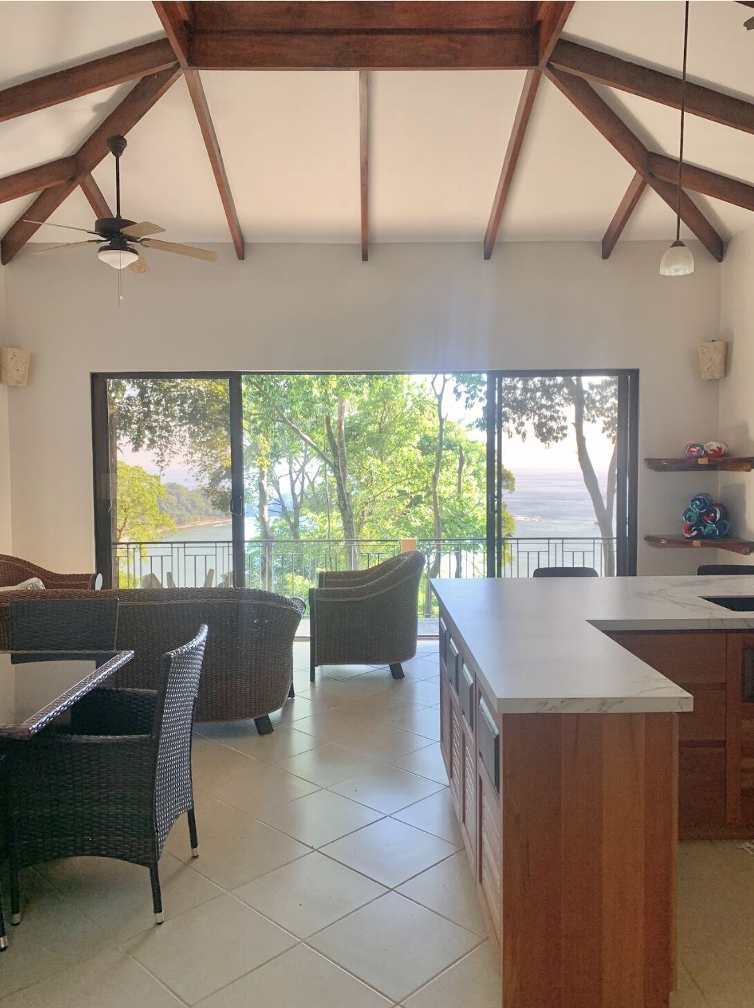 Un balcon spacieux offrant une vue sur la mer, aménagé avec des fauteuils en osier et une table à manger.
