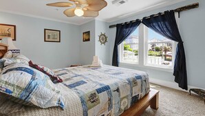 A bedroom with a bed, a ceiling fan, a window with curtains, and wall decorations. - Do you want to go to the beach "Oar Knot"? (Carolina Beach)