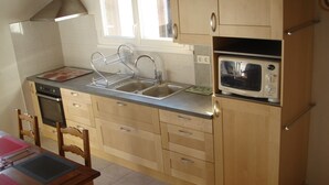 Una cocina compacta con microondas, pileta doble y armarios de madera.