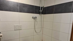 A small bathroom with a toilet, sink, and shower.
