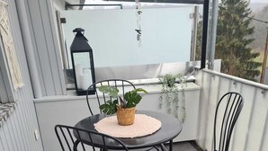 A balcony with a round table and four chairs, a potted plant, and a hanging lantern.