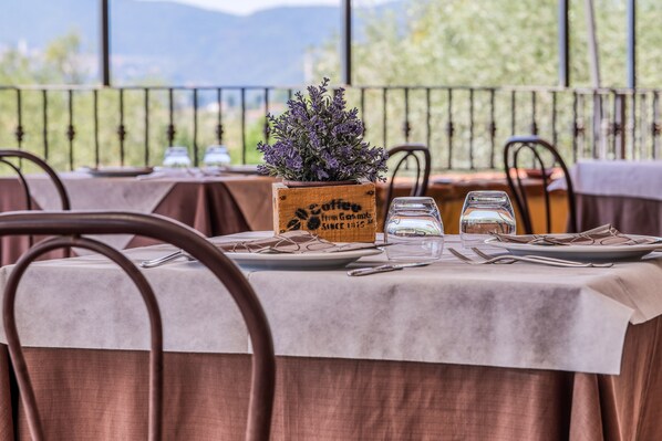 A table set for dining with a view of mountains, a wooden planter with lavender, and a sign reading "Coffee from Guatemala." - Agriturismo Regno Verde (Narni)