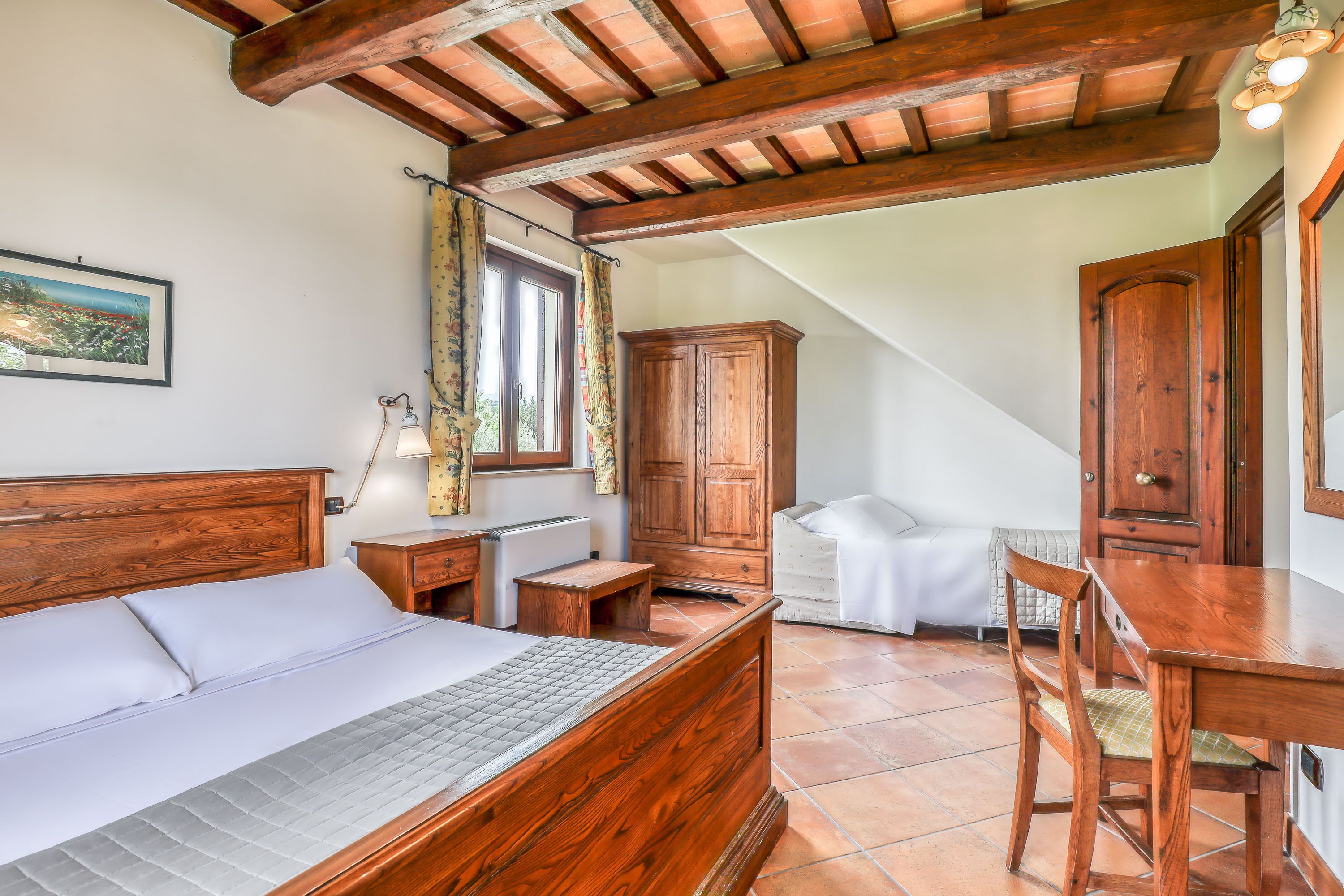Un dormitorio con una cama de madera, una mesita de noche, un escritorio y una silla.