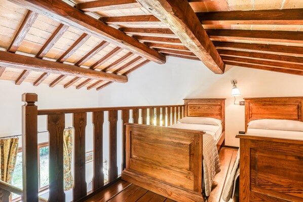 A bedroom with wooden beams, a balcony with curtains, and a nightstand with a lamp. - Agriturismo Regno Verde (Narni)