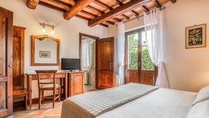 A bedroom with a bed, a desk, a chair, a television, and a window with curtains. - Agriturismo Regno Verde (Narni)