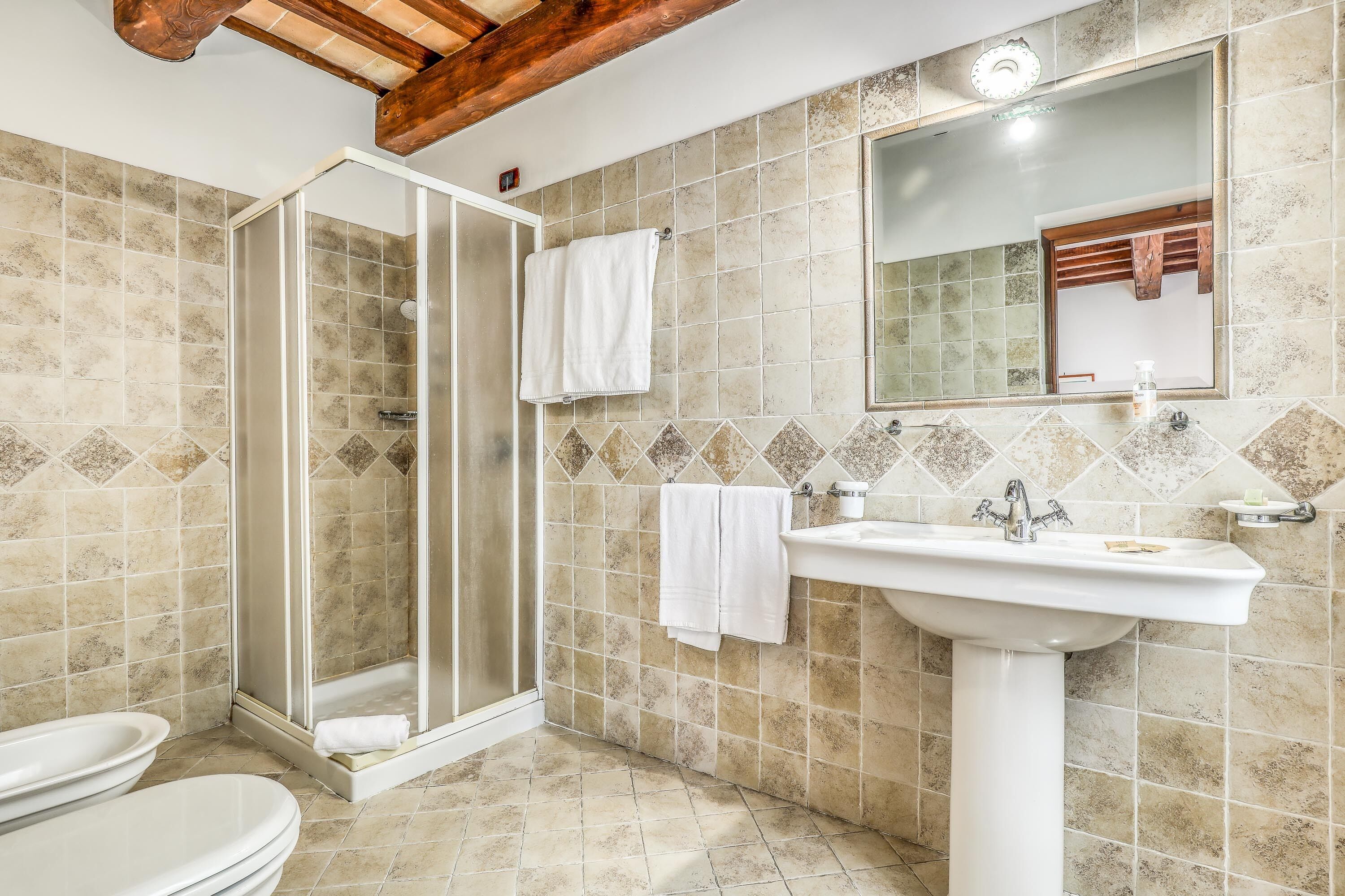 Un bagno con doccia, toilette, lavandino e specchio.