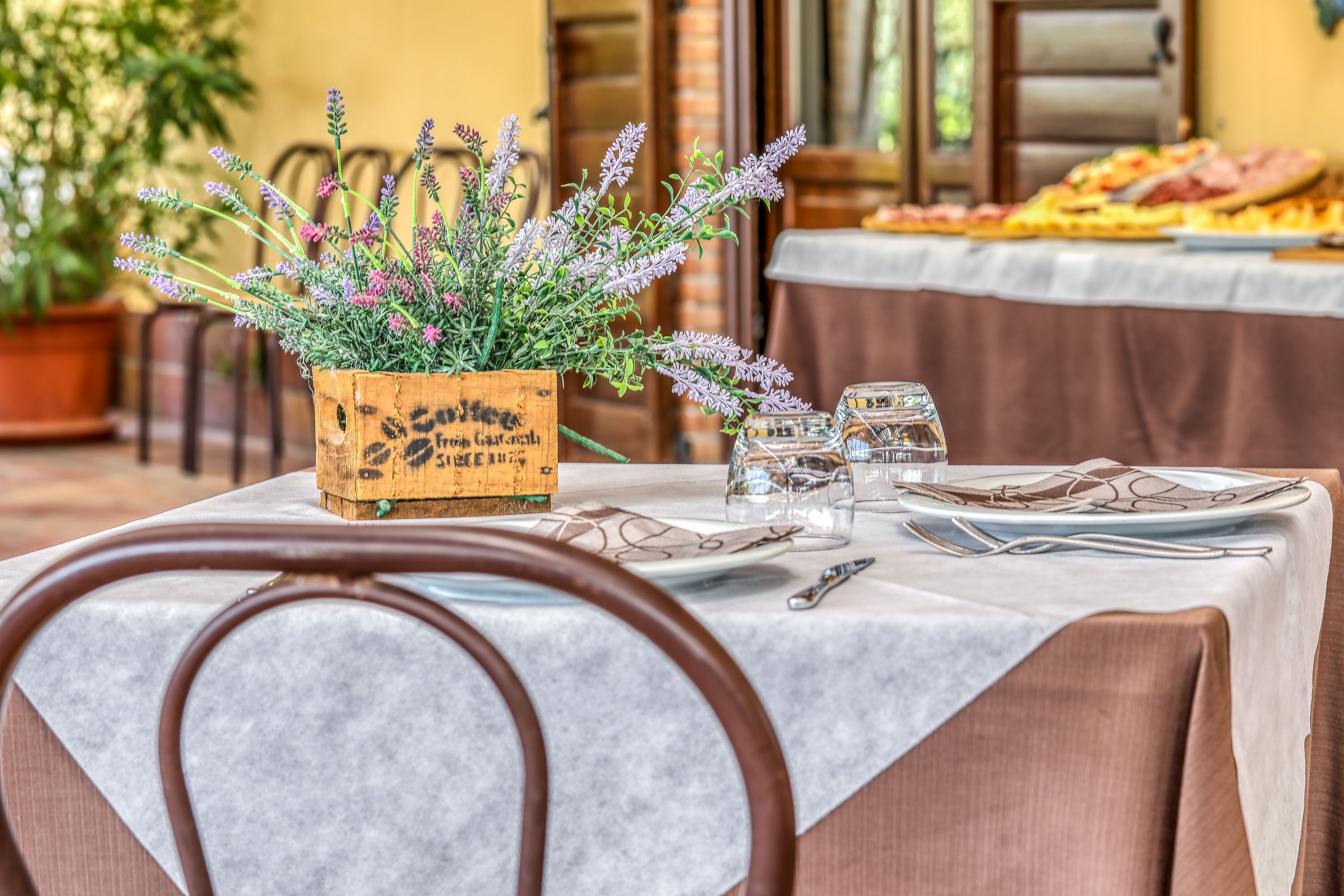 Una mesa de comedor con un centro de mesa floral, copas de vino y cubiertos.