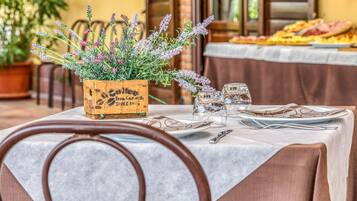 Una mesa de comedor con un centro de mesa floral, copas de vino y cubiertos.
