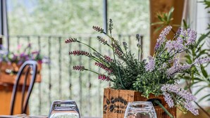 A dining table set with a wooden planter box containing flowers and a clear glass vase. - Agriturismo Regno Verde (Narni)