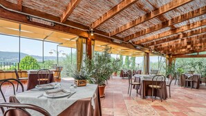 An outdoor dining area with tables and chairs, large windows, and a view of the landscape. - Agriturismo Regno Verde (Narni)