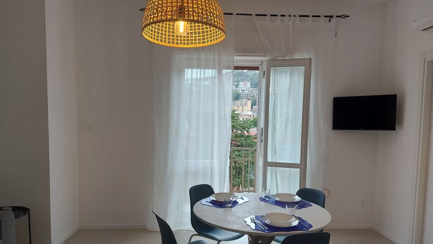 Un coin repas comprenant une table ronde, des chaises, un luminaire suspendu et un téléviseur fixé au mur.