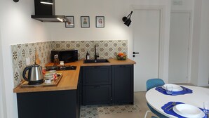 Une cuisine compacte équipée d’un four à micro-ondes, d’une bouilloire et d’un panier à fruits posé sur le plan de travail.