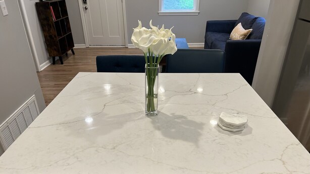 Une cuisine dotée d’un plan de travail en marbre, de deux tiroirs et d’un vase contenant des fleurs blanches.
