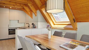A modern kitchen with wooden beams, a skylight, and a dining area with a table and chairs. - Les Marmottes by FeelFree Rentals (Vielha)