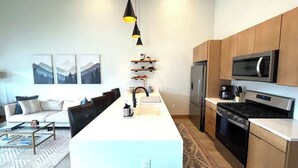 A modern kitchen with a central island, stainless steel appliances, and a dining area with a sofa and coffee table. - Elk Valley- Views for days (Crested Butte)