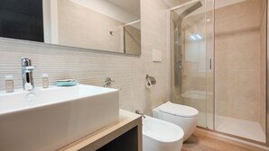 A modern bathroom with a large sink, toilet, and glass shower enclosure. - Galleria Roma Art Guesthouse (Oristano)