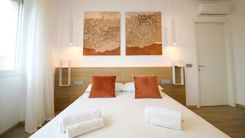 Una habitación de hotel con una cama grande, dos lámparas de pared y dos cuadros abstractos sobre la cama.
