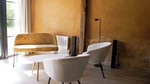 A modern living room with a sofa, two armchairs, a coffee table, and a floor lamp. - Oude Schuur Omgetoverd tot Moderne Gîte (montchevrier)