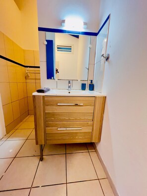 Une salle de bain avec un meuble-lavabo en bois, un miroir et un lavabo.