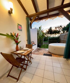 Une terrasse avec une table et des chaises, un jacuzzi et une vue sur le jardin.