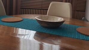 Una mesa de comedor con un tazón, individuales y sillas.