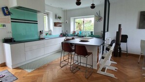 Une cuisine moderne dotée d’un îlot central, de tabourets de bar et offrant une vue sur l’extérieur.